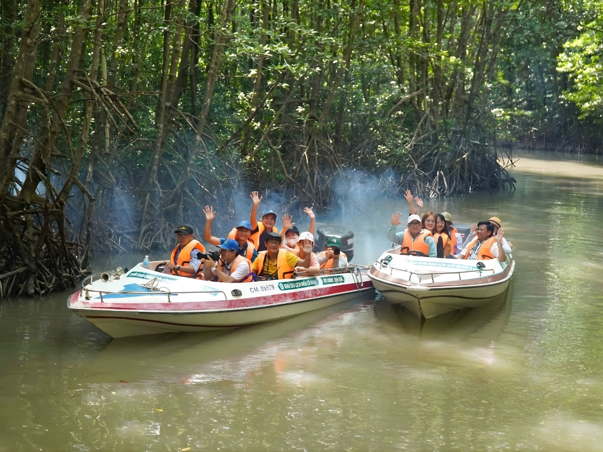 Du khách mặc áo phao vui vẻ ngồi thuyền máy khám phá rừng trên sông.