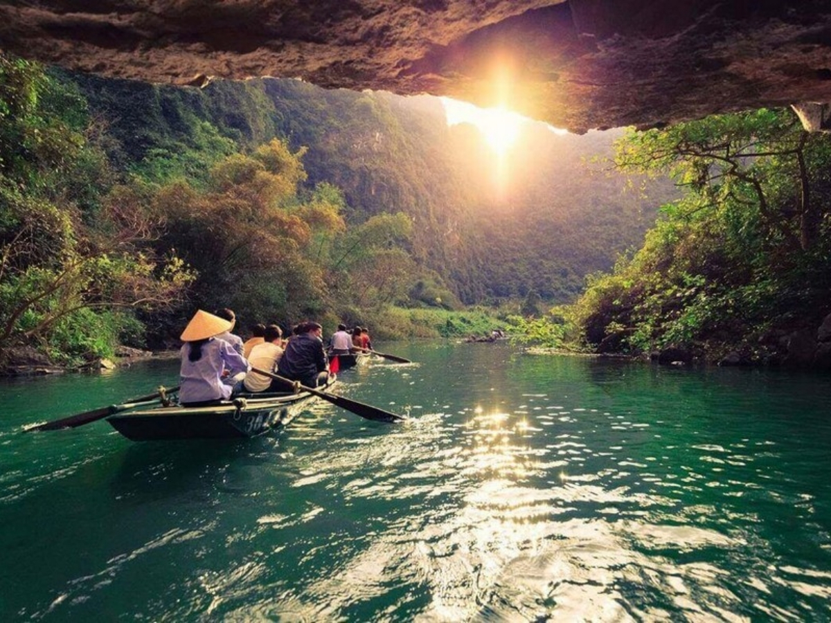 Du khách ngồi thuyền chèo qua hang đá và ngắm khung cảnh nên thơ.