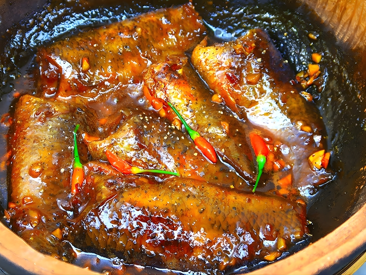 Món cá kho đậm đà nấu trong niêu đất với ớt thơm truyền thống.