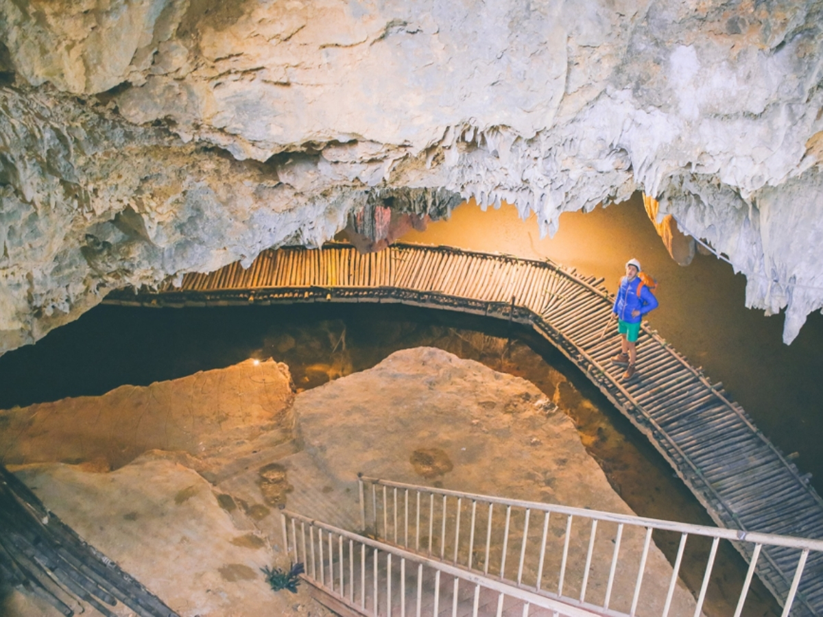 Du khách đi bộ trên cầu gỗ khám phá hang động đá vôi vào buổi sáng.