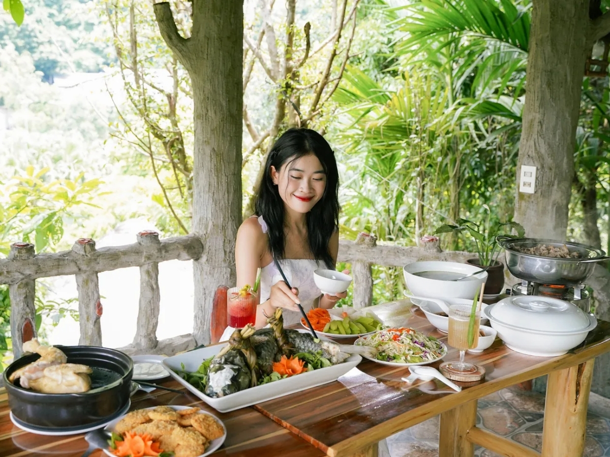 Du khách thưởng thức bữa ăn truyền thống trong không gian xanh mát.